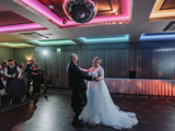 o	Bride and groom share first dance under colourful lights on dancefloor during last minute evening wedding reception in Scotland.