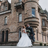 Wide shot of couple standing in front of castle