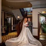 bride and groom at base of ornate stairwell inside boclair house