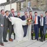 Groomsmen holding up bride and smiling