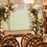 Wedding ceremony setup in Boclair House Grand Ballroom in Bearsden, Glasgow, with mirrored pillars, gold chandeliers, and white aisle.