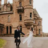 Couple holding hands walking away from castle