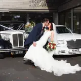 Couple kissing infront of wedding cars