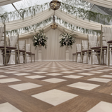 An elegant wedding ceremony set up at the Pavilion at Cornhill Castle in Biggar, Scotland, featuring wooden flooring and neatly arranged white chairs for attendees.